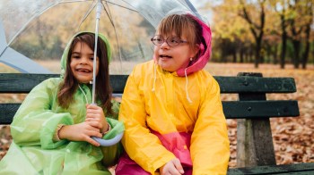 2个女孩在雨天坐在公园 享受3月生日